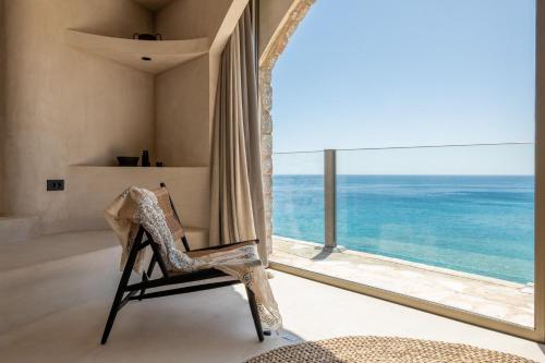 a room with a chair and a large window at Stone Luxury Suites - Adults Only in Archangelos