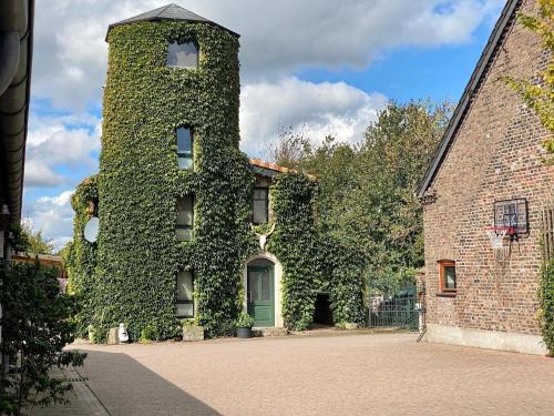 an ivy covered building with a green door at Turm auf altem Bauernhof in Götterswickerhamm