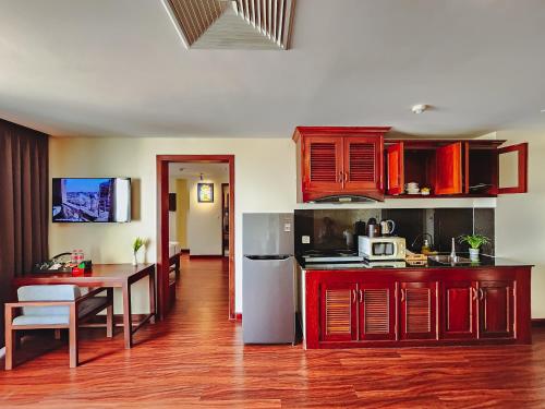 a kitchen with red cabinets and a table in a room at Poulo Wai Hotel & Apartment in Phnom Penh