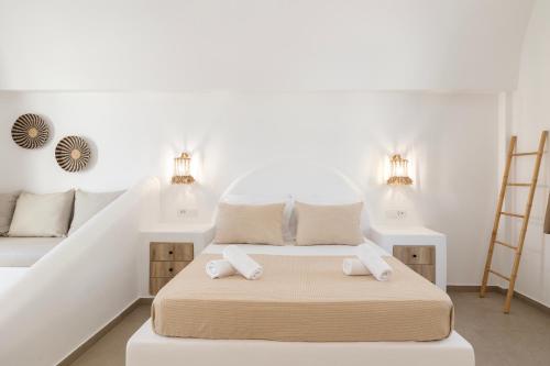 a white bedroom with a bed with two towels at Commercio Suites Santorini in Emporio Santorini