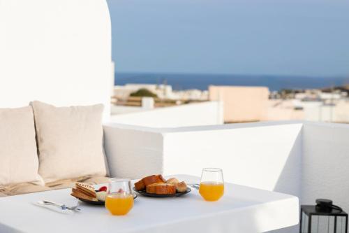 a table with a plate of food and two glasses of orange juice at Commercio Suites Santorini in Emporio Santorini