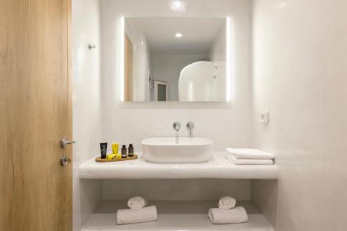 a white bathroom with a sink and a mirror at Commercio Suites Santorini in Emporio Santorini