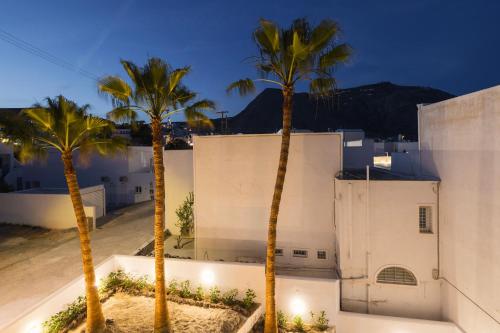 two palm trees in front of a white building at Commercio Suites Santorini in Emporio Santorini