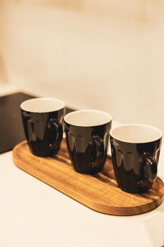 three black cups sitting on a wooden tray at Commercio Suites Santorini in Emporio Santorini