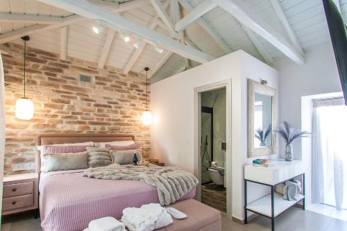 1 dormitorio con cama rosa y pared de ladrillo en Frina's House Skiathos, en Skiathos