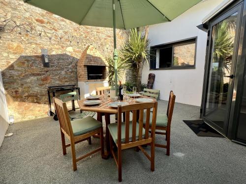 une table en bois avec des chaises et un parasol dans l'établissement Magnifique Loft 160m2 x 6 pers Proche plage, à Les Sables-dʼOlonne