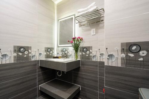 uma casa de banho com um lavatório e um vaso de flores em Lucky Star Hotel Nguyen Trai Q5 em Ho Chi Minh