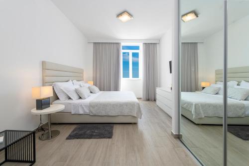 a white bedroom with two beds and a mirror at Banje Beach Oasis Apartment in Dubrovnik