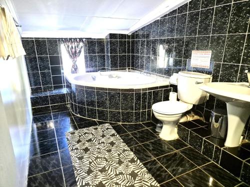 a bathroom with a tub and a toilet and a sink at KatiKati Eco Lodge in White River