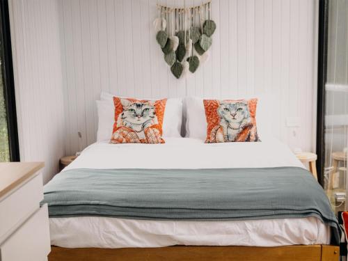 ein Schlafzimmer mit einem Bett mit zwei Katzen-Kissen in der Unterkunft Grassmere Orchard in Napier