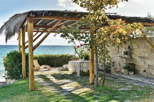 a table under a pergola next to the ocean at Azure Coast Seafront Retreat in Mola Kalyva