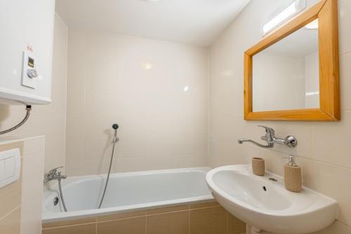 a white bathroom with a sink and a bath tub at Wellness hotel Chata Jana in Lopeník