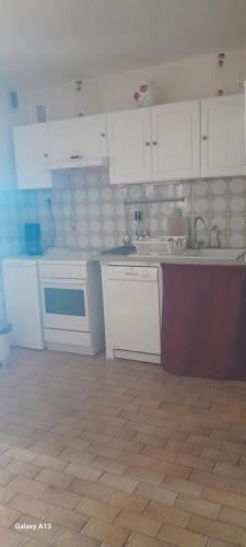 a kitchen with white cabinets and a wooden floor at F3 RDC villa vue mer 180 face à la pointe de Giens in Carqueiranne