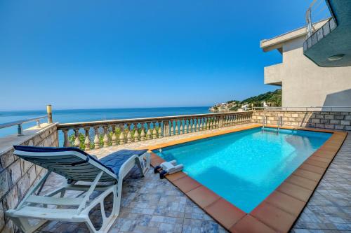 a swimming pool with two chairs and the ocean at Villa Blue Bay in Kruče