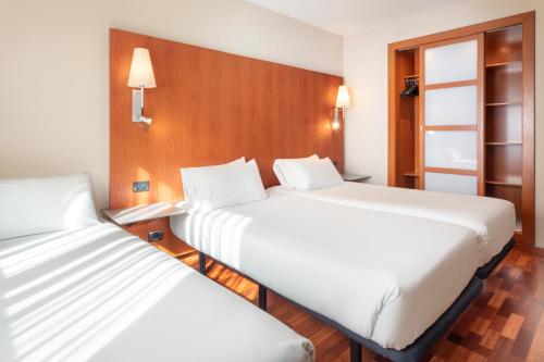 2 bedden in een hotelkamer met witte lakens bij B&B Hotel Ciudad de Lleida in Lleida