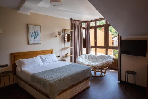a bedroom with a bed and a chair and a window at Apartamentos San Jorge in Nueva de Llanes