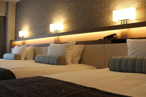 two beds in a hotel room with lights on the wall at Hotel Sardonyx Tokyo in Tokyo