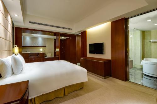 um quarto com uma cama, uma banheira e uma televisão em Crowne Plaza Yantai Sea View, an IHG Hotel em Yantai