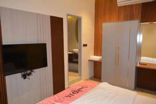 a bedroom with a bed and a flat screen tv at Myspace Saroja Suites in Gulbarga