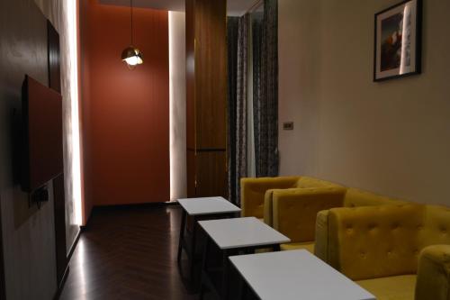 a living room with two tables and a yellow couch at Myspace Saroja Suites in Gulbarga