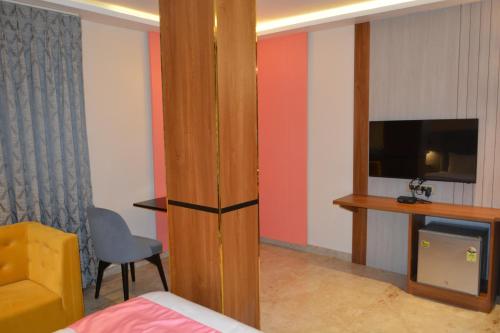 a room with a bed and a tv and a chair at Myspace Saroja Suites in Gulbarga