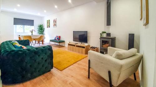 里斯本的住宿－Green Charm House Lisbon，客厅配有两把椅子、一台电视和一张桌子