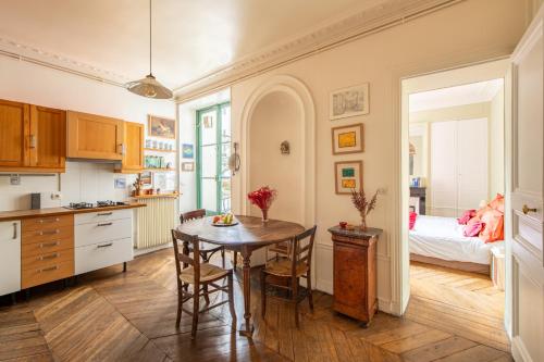 une cuisine et une salle à manger avec une table et un lit dans l'établissement Géranimus Enghien, à Paris