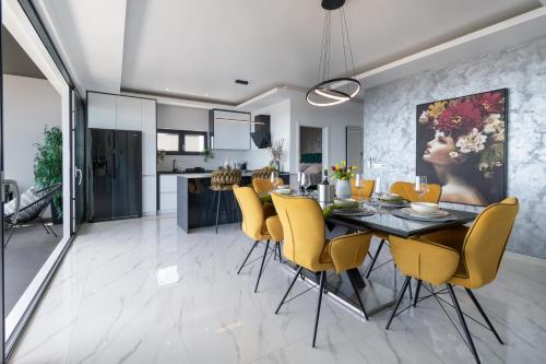 a kitchen and dining room with a dining table and yellow chairs at Lux Penthouse Panoramic View with jacuzzi in Makarska