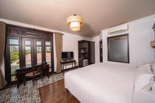 a bedroom with a large white bed and a television at Anja Beach Resort & Spa in Phu Quoc