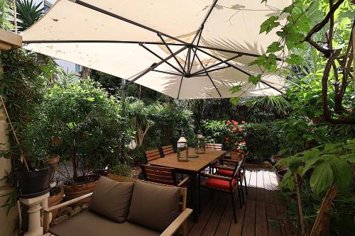 - une table en bois avec un parasol dans le jardin dans l'établissement Appartement L'Etang Cannes Pointe Croisette, à Cannes