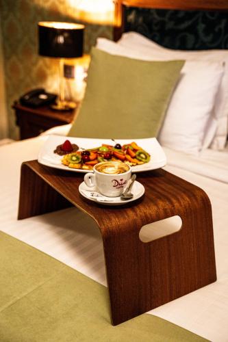 a tray of food and a cup of coffee on a bed at Envy Hotel in Durrës