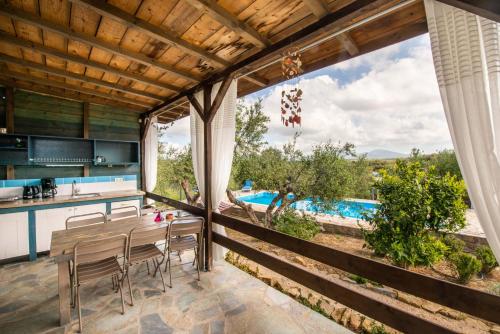 a kitchen and dining room with a view of a pool at Hakuna Matata Holidays wooden lodge with airco & pool in Greek Olive Grove in Methoni