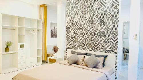 a bedroom with a large white bed with a wall at MIDMOST Villa Hotel in Can Tho