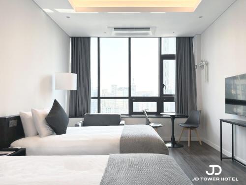 a hotel room with a bed and a desk and window at JD Tower Hotel in Seoul