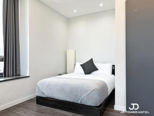 a bedroom with a bed with white sheets and a window at JD Tower Hotel in Seoul