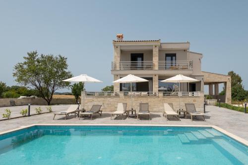a villa with a swimming pool in front of a house at Black Lotus Pool Villa, Afitos #FeelsLikeHome in Afitos