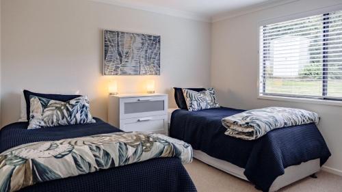 a bedroom with two beds and a window at Sandy Cottage in Narrawallee