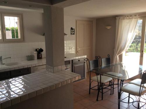 une cuisine avec une table, des chaises et une table en verre dans l'établissement Appartement rez de jardin de villa avec piscine, à Roquefort-les-Pins