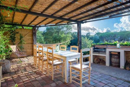 a wooden table and chairs under a wooden pergola at Mas Dels Arcs Con piscina Muy cerca de la playa in Calonge