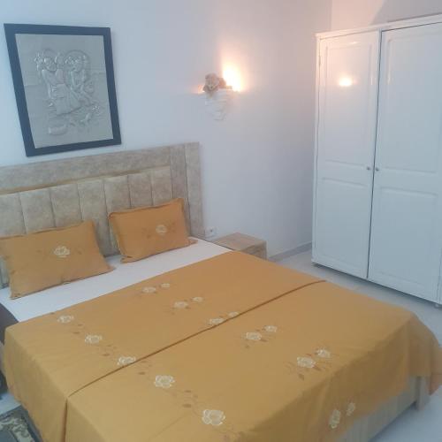 a bedroom with a bed with a yellow blanket on it at Coquet RDC in Borj el Khessous