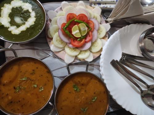 a table with a plate of food and two bowls of soup at Anugraha Homestay in Rāmnagar
