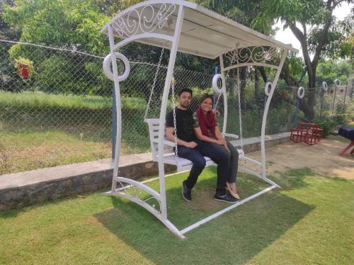 two people sitting on a swing in a gazebo at Anugraha Homestay in Rāmnagar