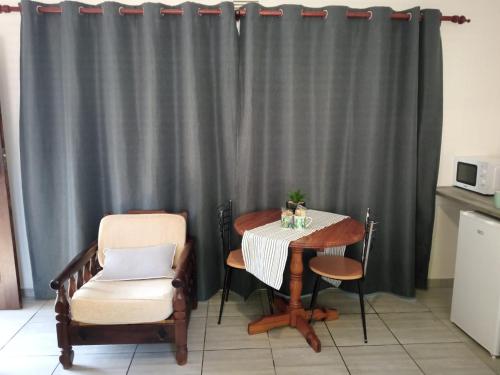 a table and chairs in a kitchen with a gray curtain at Cozy Corner in Groblersdal