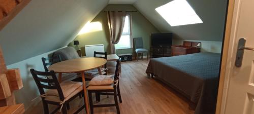 une chambre avec un lit, une table et des chaises dans l'établissement Le petit Herils, à Maisons