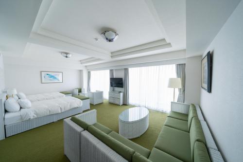 een woonkamer met een bank en een bed bij Hotel Atollemerald Miyakojima in Miyako Island