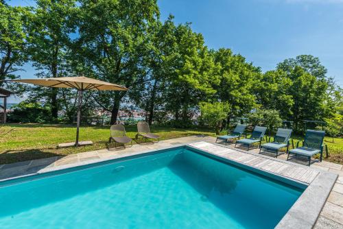 a swimming pool with chairs and an umbrella at Casa Rita, Charming House with pool, Asti in Asti