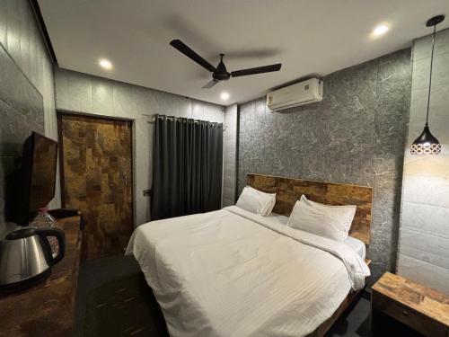 a bedroom with a white bed and a ceiling fan at Aariv Inn BAGA BEACH in Baga