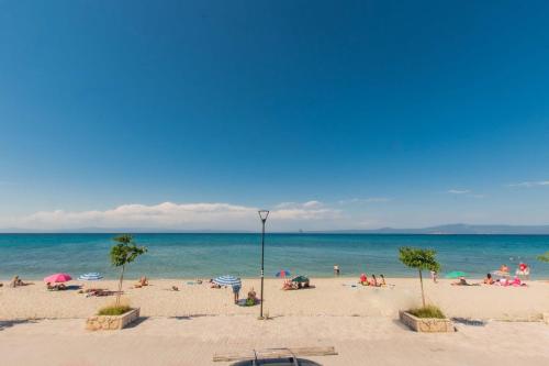 a group of people on a beach with the ocean at Houseloft Horizon Seafront Pefkochori in Pefkohori