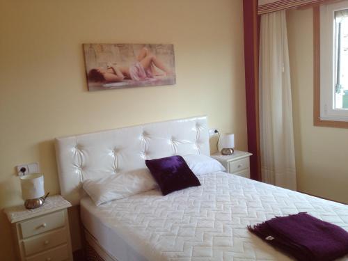 a bedroom with a white bed with a purple pillow at Apartamento en A Revolta, Sanxenxo in Sanxenxo