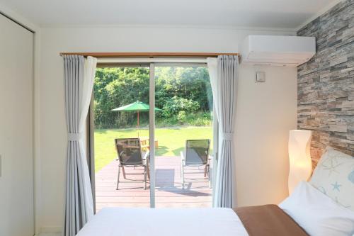 une chambre avec un lit et un patio avec une table et des chaises dans l'établissement スターダストヴィラミルキーウェイ, à Fukai